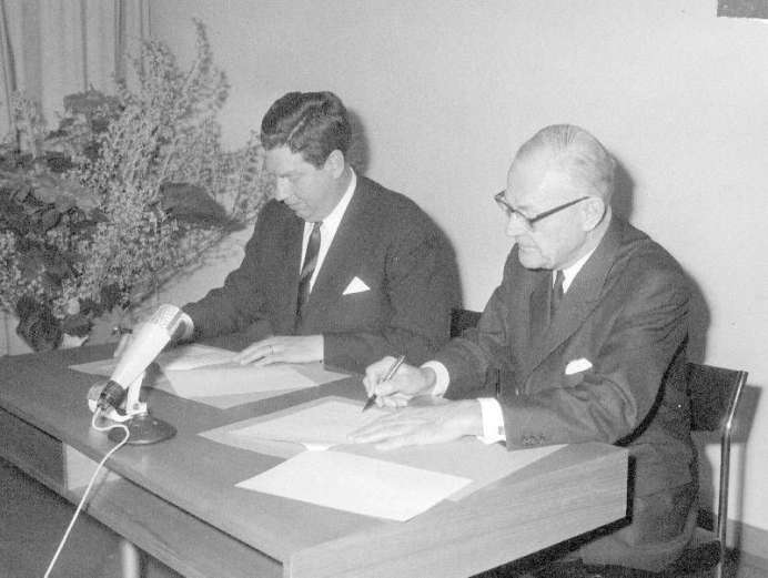 Zwei Männer an einem Tisch beim unterschreiben von Papieren