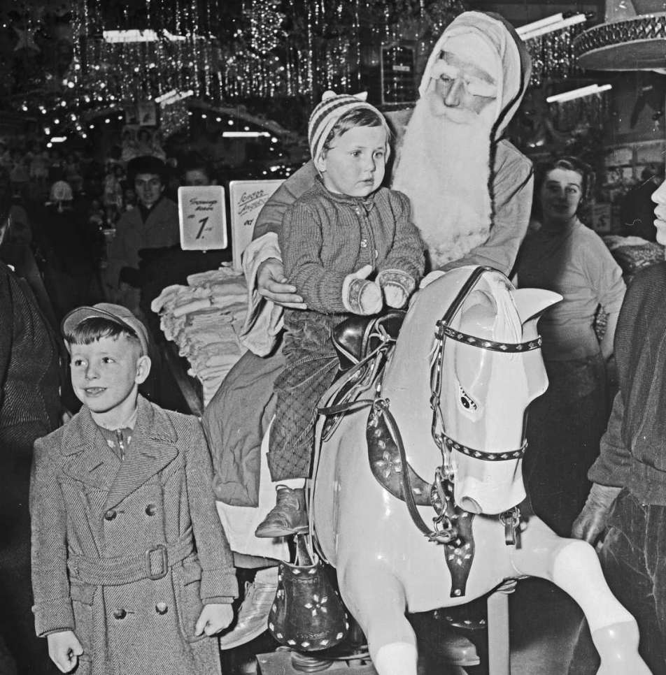 schwarz-weiß Bild zu Weihnachten in 1960er Jahren, das zwei Kinder mit dem Nikolaus zeigt