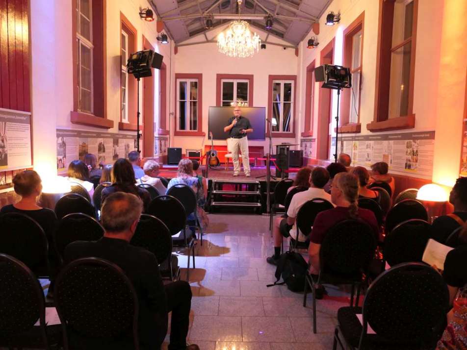 farbiges Bild, das eine Veranstaltung mit Menschen in den Räumlichkeiten von RomnoKher zeigt